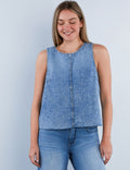 A woman wearing a sleeveless denim tank top in a washed blue color, paired with blue jeans.