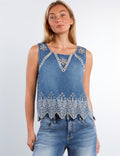 Woman wearing a denim tank top with lace details on a plain background